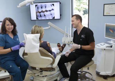 Dentist and hygienist talking with a patient at Deem Dentistry